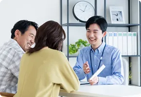 中年夫婦に笑顔で説明をするビジネスマン